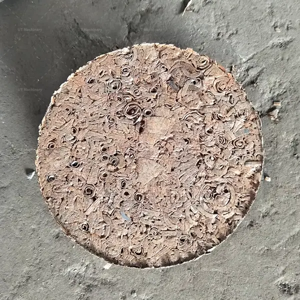 Top-down close-up of a tightly compressed brass shavings briquette block showing perfect metal consolidation.