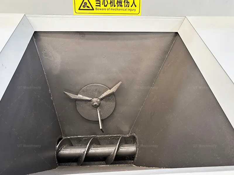 Forced screw feeding hopper design with a mechanical agitator paddle to prevent bridging of fluffy steel turnings and cast iron borings.