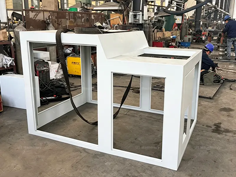 Heavy-duty steel structural frame welding and assembly for the metal briquetting machine inside the UT Machinery production workshop.