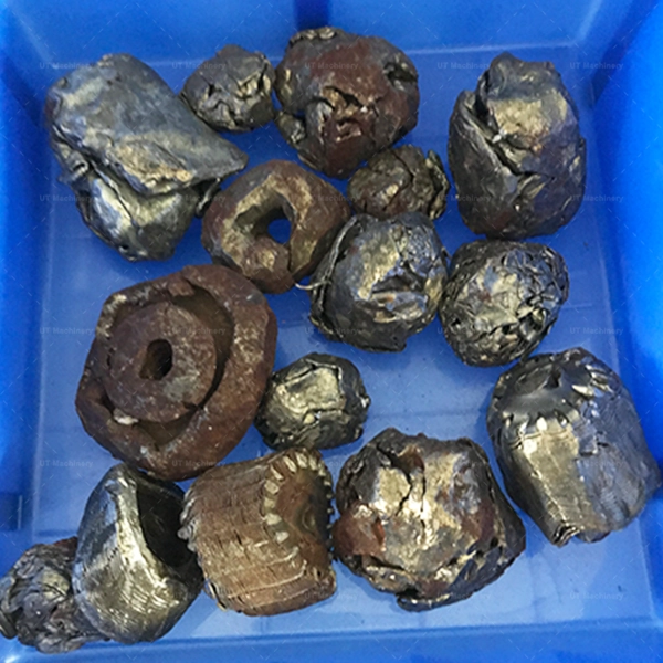 Assorted large particles of crushed copper, brass, and steel machining scrap, stored in a blue bin.