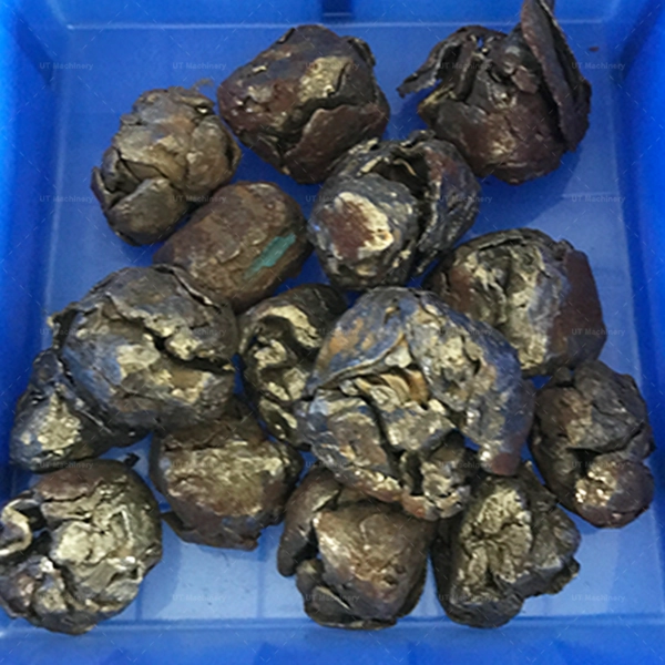 Large, compacted granules of crushed iron borings and mixed metal waste, prepared for melting.