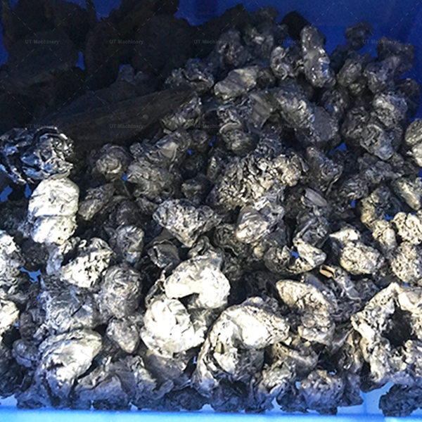 Medium-sized crushed metal chips from turning operations, showing a dense and fragmented form in a blue container.