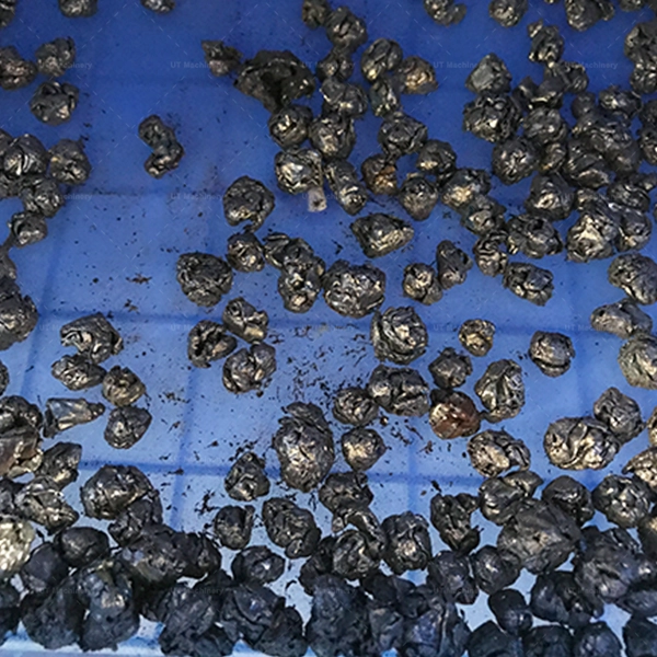 Small, condensed pieces of crushed aluminum machining swarf in a blue bin, ready for recycling.